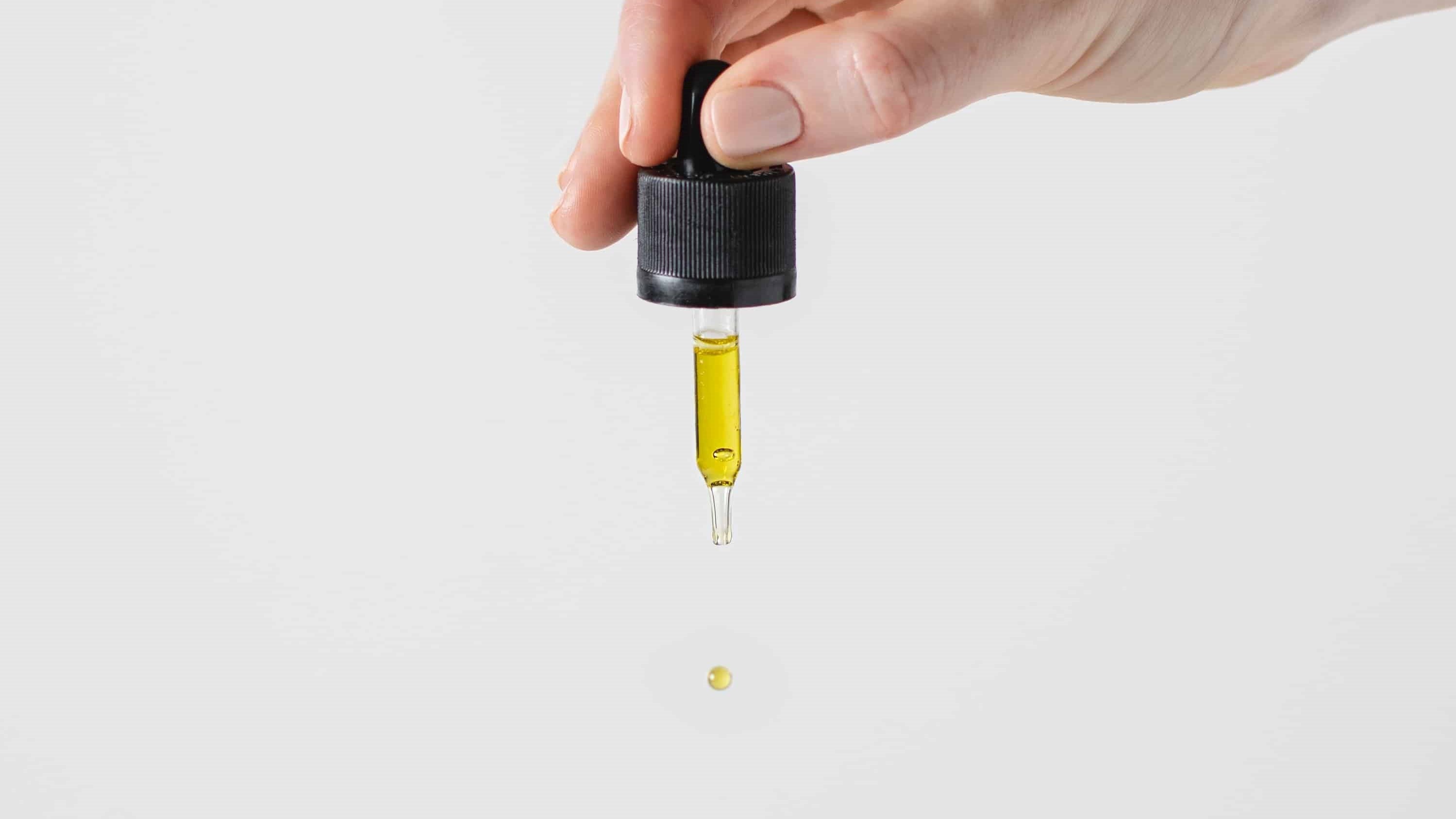 Eine Hand tropft mit Hilfe einer Pipette CBD Öl auf die Oberfläche